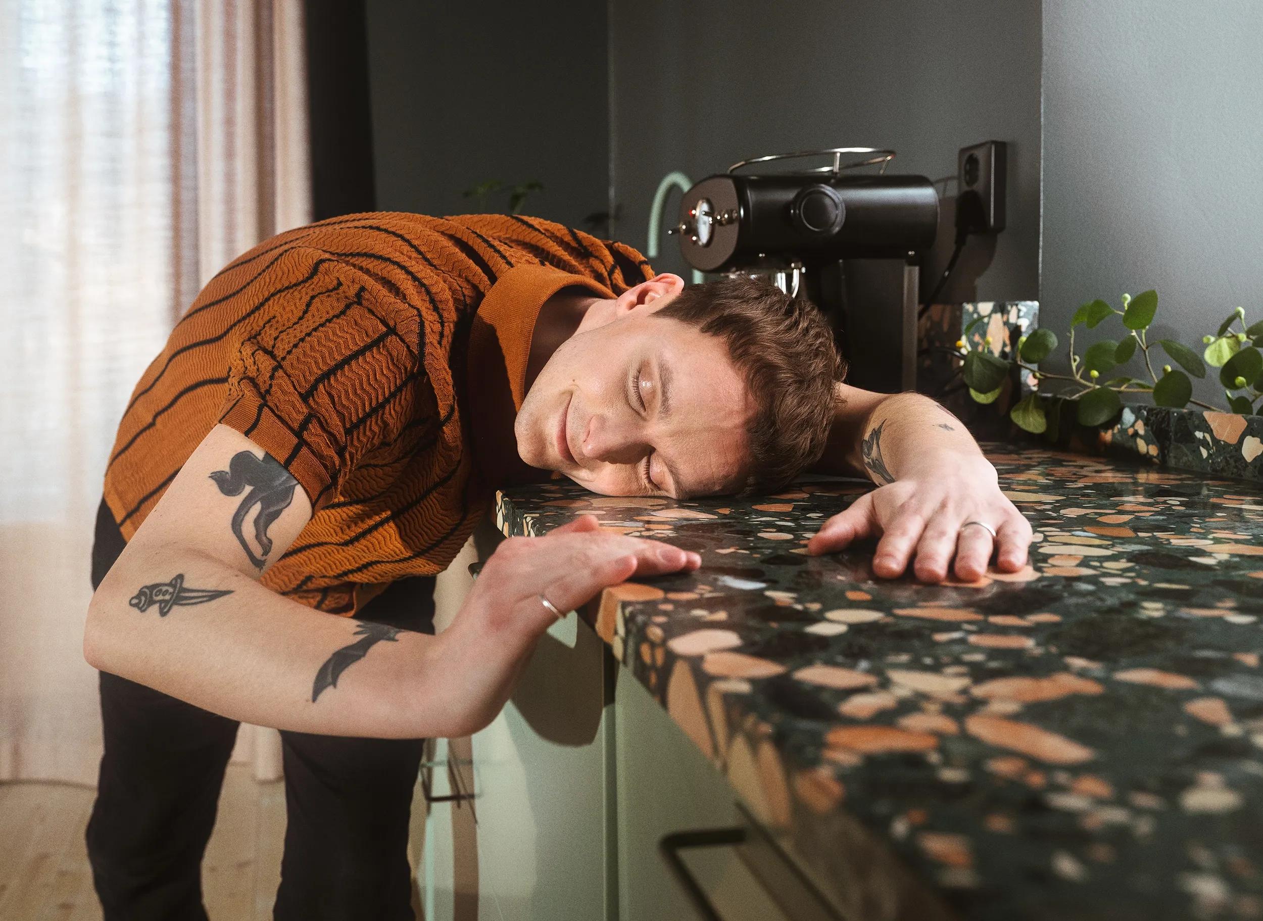 En man är så nöjd med sitt nyrenoverade kök att han kramar sin bänkskiva