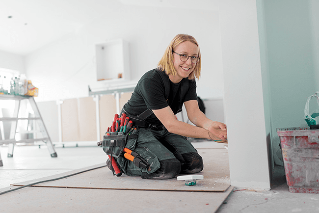 Kvinnlig behörig elektriker drar el under renovering