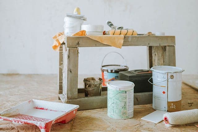 Renovering pågår, målarburkar, penslar och burkar står på golvet